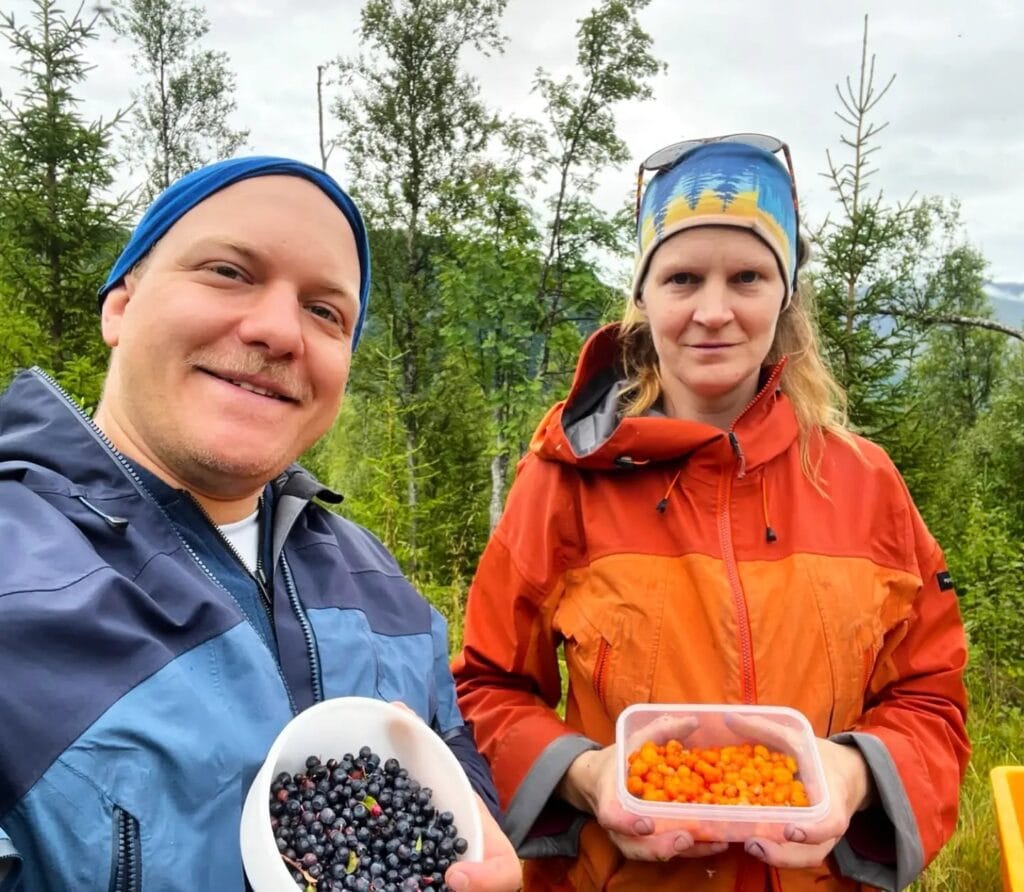 Zwei Menschen zeigen Schalen mit frisch gepflückten Blaubeeren und Moltebeeren