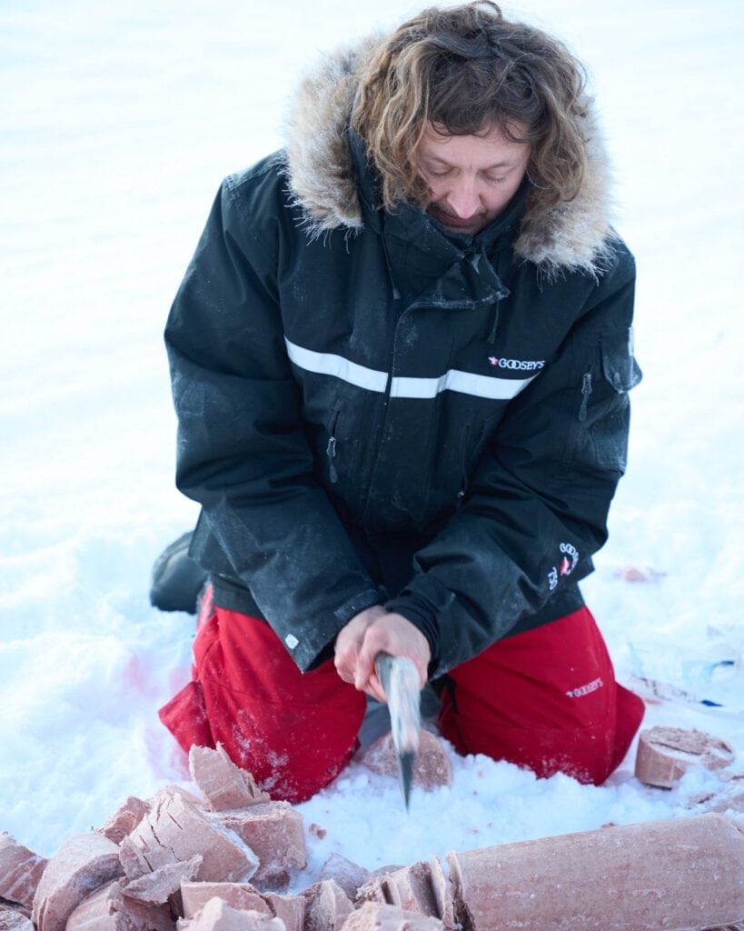 Gefrorenes Fleisch wird im Schnee für das Hundefutter klein gehackt